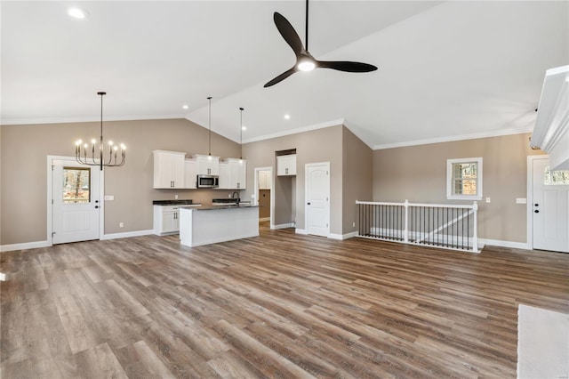 unfurnished living room featuring ceiling fan with notable chandelier, baseboards, lofted ceiling, and ornamental molding