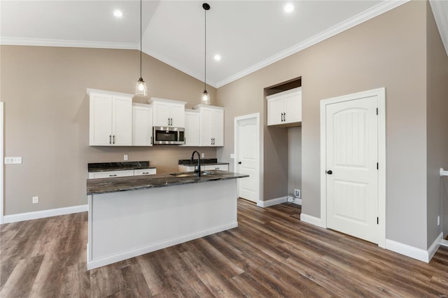 kitchen featuring a sink, stainless steel microwave, a kitchen island with sink, and ornamental molding