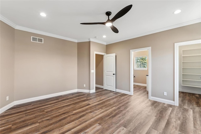 unfurnished bedroom with crown molding, a spacious closet, baseboards, and visible vents