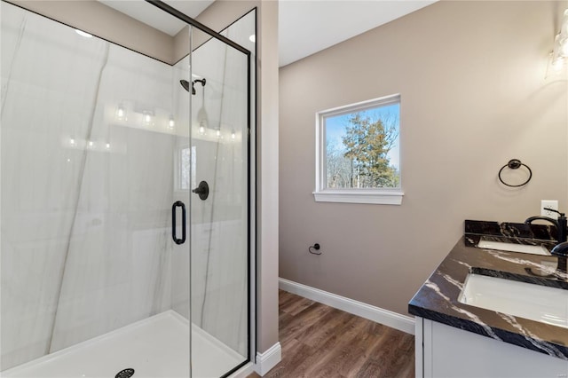 bathroom featuring a sink, baseboards, wood finished floors, and a shower stall