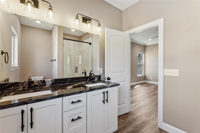 bathroom with a sink, baseboards, wood finished floors, and a shower stall