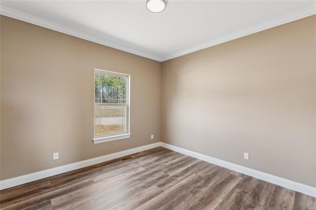 spare room featuring visible vents, baseboards, wood finished floors, and crown molding