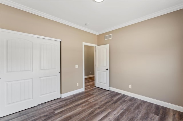 unfurnished bedroom with a closet, visible vents, dark wood-type flooring, and baseboards