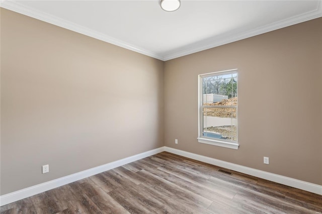 unfurnished room with visible vents, ornamental molding, baseboards, and wood finished floors