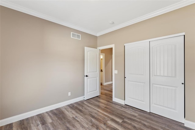 unfurnished bedroom with visible vents, ornamental molding, baseboards, and wood finished floors