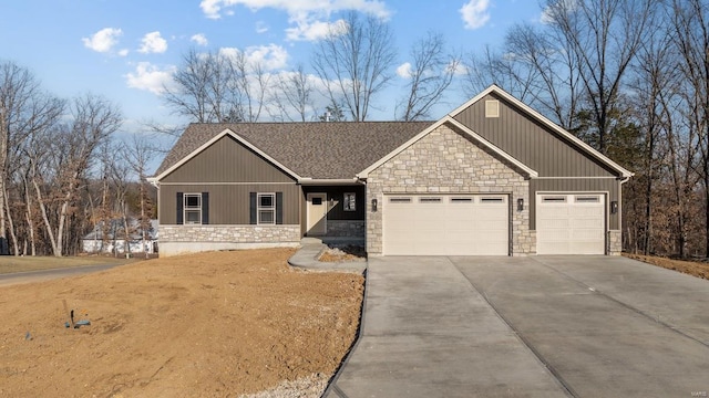 craftsman-style house featuring an attached garage, stone siding, and driveway