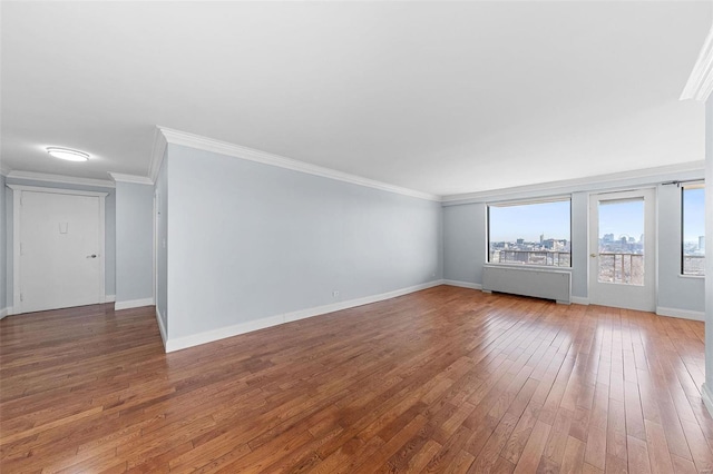 spare room featuring hardwood / wood-style floors, baseboards, and ornamental molding