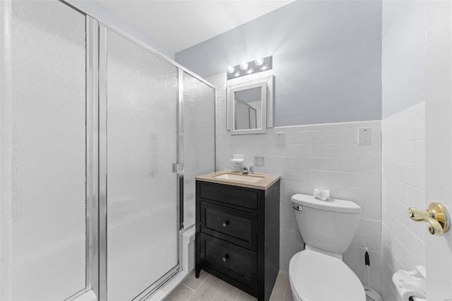 bathroom with a shower with shower door, toilet, tile walls, and vanity