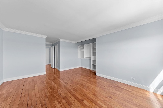 unfurnished living room featuring hardwood / wood-style floors, crown molding, and baseboards