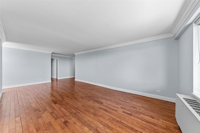 spare room featuring baseboards, crown molding, and hardwood / wood-style flooring