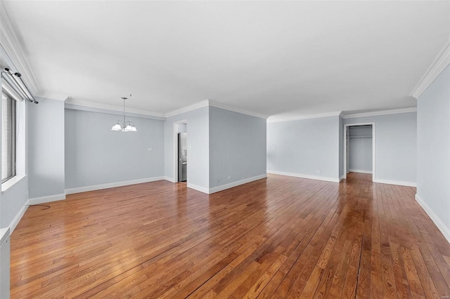 empty room with baseboards, wood-type flooring, a chandelier, and ornamental molding