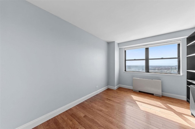 spare room with hardwood / wood-style flooring, radiator heating unit, and baseboards