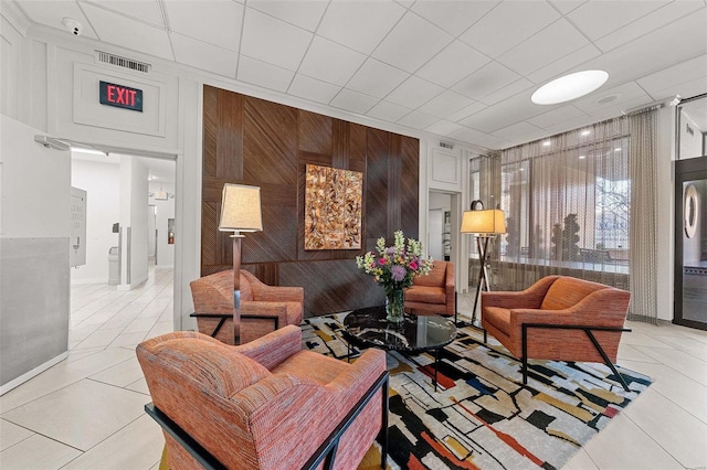 living room featuring light tile patterned floors, visible vents, and wooden walls