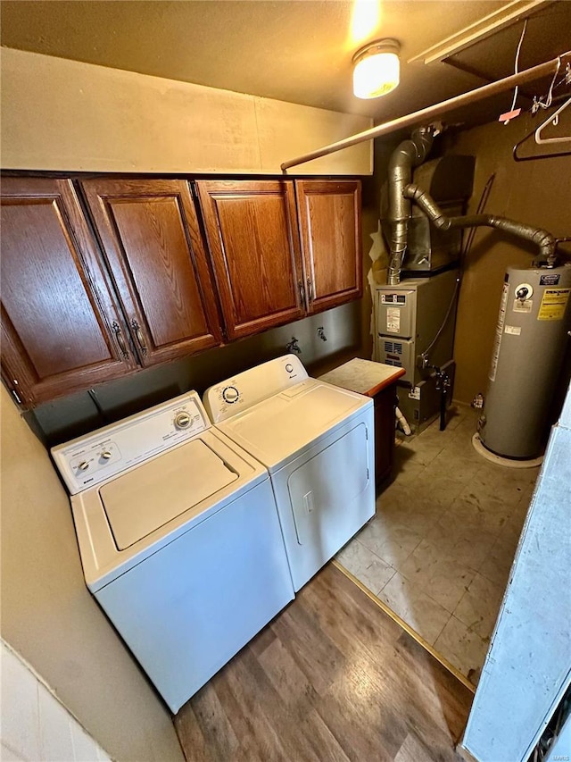 washroom with heating unit, cabinet space, washing machine and dryer, and water heater