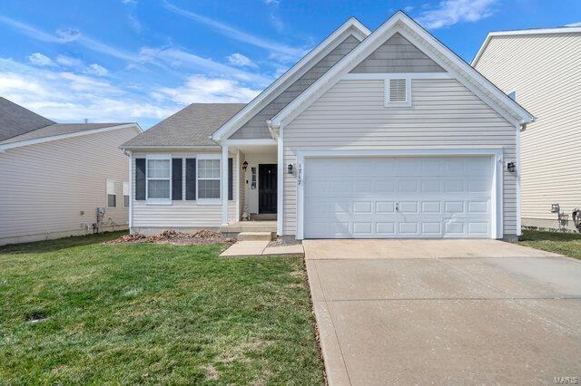 view of front of property featuring a garage, concrete driveway, and a front yard