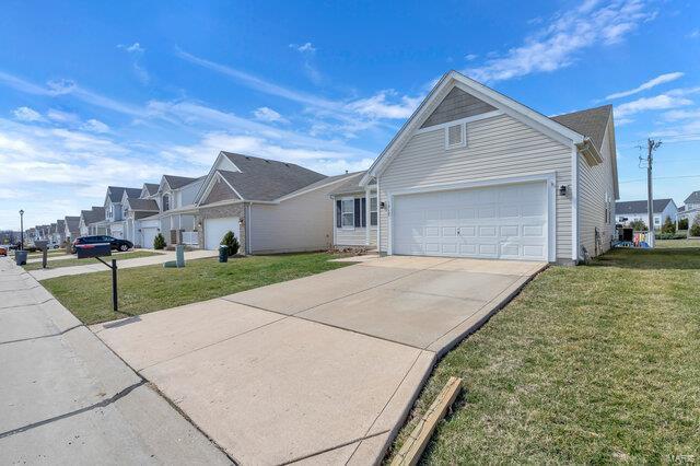 view of side of home featuring a garage, a yard, a residential view, and driveway