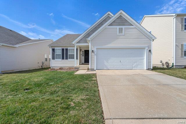 view of front facade with a front yard, concrete driveway, and a garage