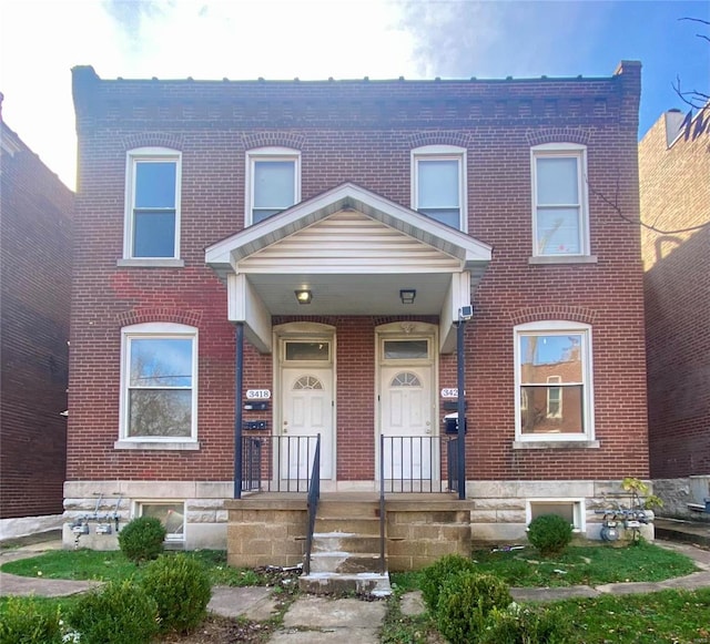 view of property with brick siding and a porch