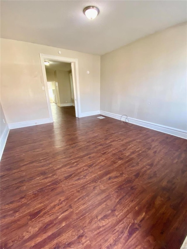 spare room featuring dark wood-style floors and baseboards