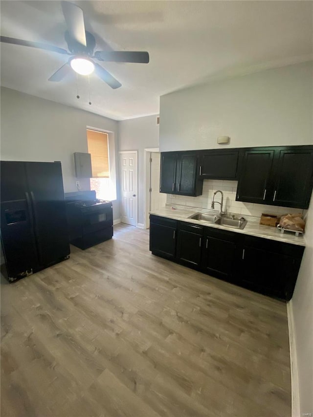 kitchen with a ceiling fan, light wood-style flooring, a sink, black fridge with ice dispenser, and dark cabinets