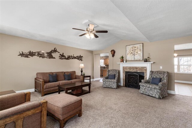 living room featuring ceiling fan, baseboards, lofted ceiling, carpet floors, and a fireplace