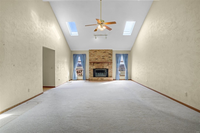 unfurnished living room featuring a skylight, a fireplace, high vaulted ceiling, and ceiling fan