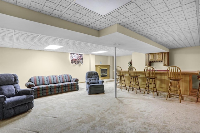 living room featuring a fireplace with raised hearth, carpet floors, and indoor bar