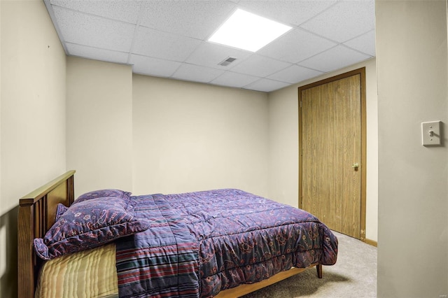 carpeted bedroom with visible vents and a drop ceiling