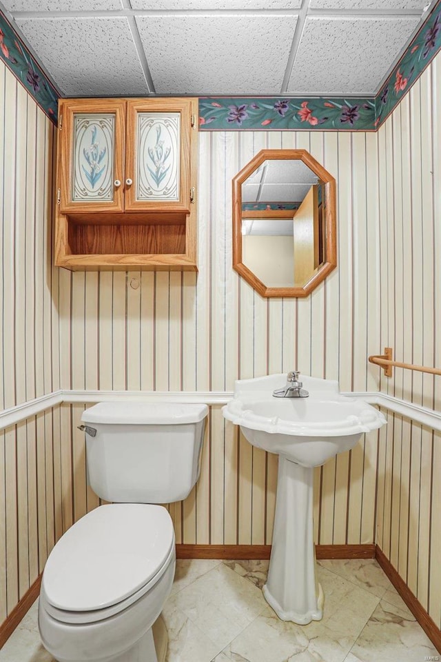 bathroom with toilet, a paneled ceiling, and baseboards