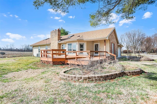 rear view of property featuring a garage, a yard, a wooden deck, and a chimney