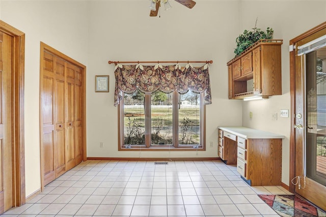 kitchen with visible vents, a ceiling fan, a high ceiling, light countertops, and light tile patterned floors