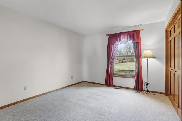 unfurnished room with light carpet, visible vents, and baseboards