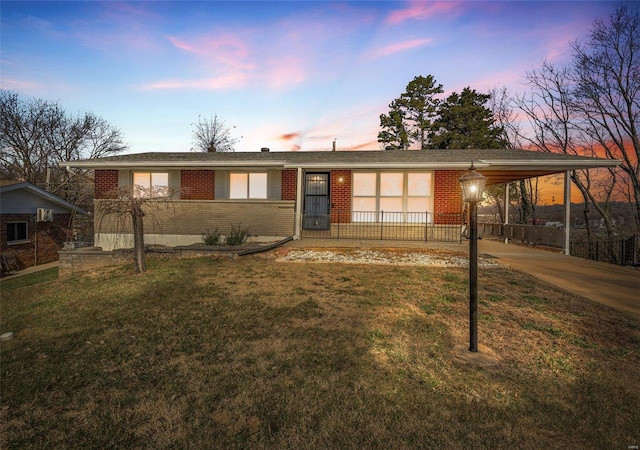 ranch-style home featuring brick siding, an attached carport, and a front lawn