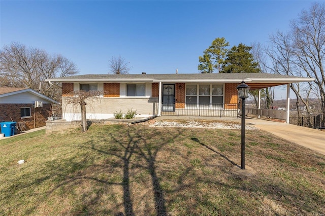 ranch-style home featuring brick siding, concrete driveway, a front yard, and a carport