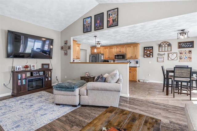 living area featuring baseboards, lofted ceiling, and wood finished floors