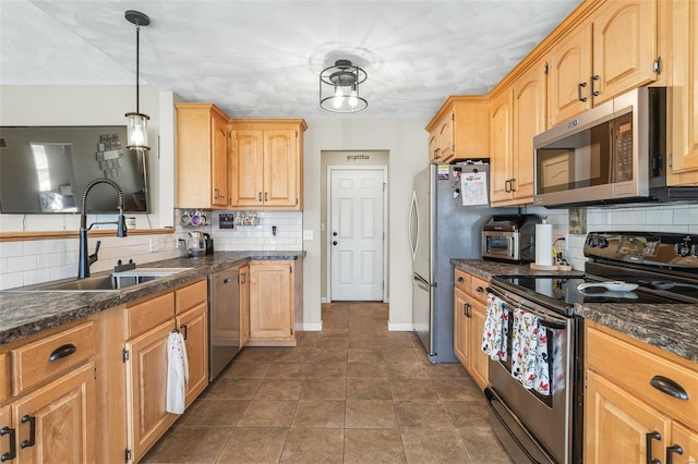 kitchen featuring dark countertops, backsplash, baseboards, stainless steel appliances, and a sink