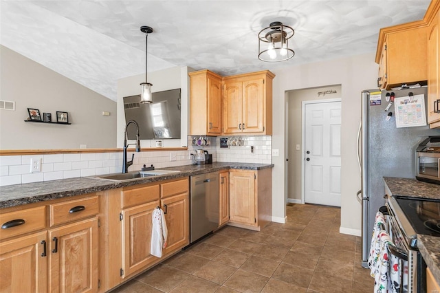 kitchen with dark countertops, visible vents, appliances with stainless steel finishes, and a sink