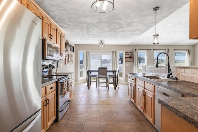 kitchen featuring dark countertops, a healthy amount of sunlight, appliances with stainless steel finishes, and a sink