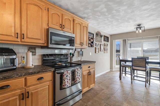 kitchen featuring tile patterned flooring, decorative backsplash, appliances with stainless steel finishes, and baseboards