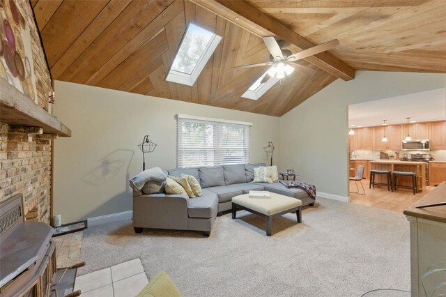 living area featuring baseboards, light colored carpet, a skylight, wood ceiling, and ceiling fan
