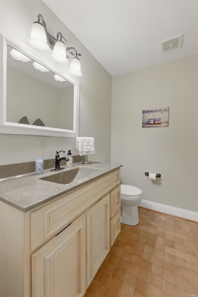 bathroom featuring vanity, toilet, and baseboards
