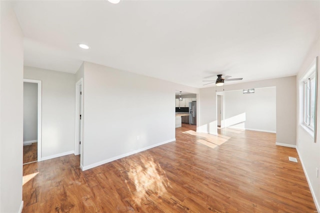 unfurnished living room featuring light wood-style flooring, baseboards, visible vents, and ceiling fan