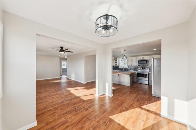 kitchen featuring baseboards, stainless steel appliances, dark wood-type flooring, tasteful backsplash, and open floor plan