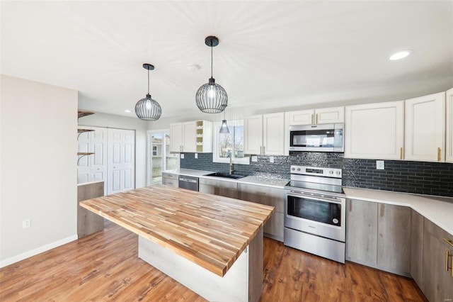 kitchen with a sink, stainless steel appliances, tasteful backsplash, and wood finished floors