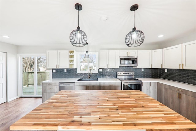 kitchen with a sink, tasteful backsplash, wood counters, and stainless steel appliances