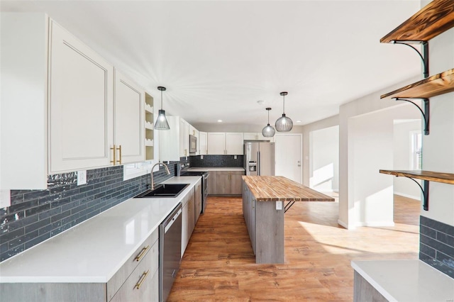 kitchen featuring light wood-style flooring, a sink, appliances with stainless steel finishes, wood counters, and backsplash