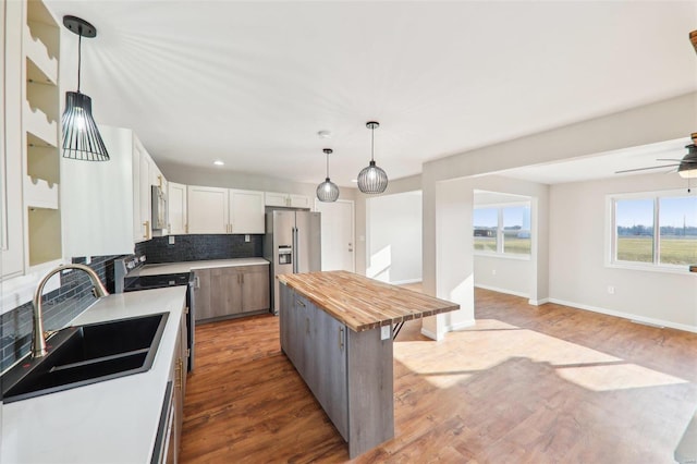 kitchen featuring a ceiling fan, wooden counters, stainless steel appliances, a sink, and backsplash