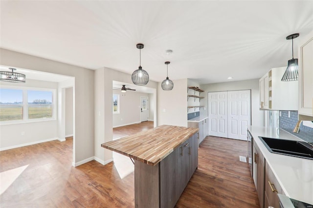 kitchen featuring a wealth of natural light, dark wood finished floors, butcher block counters, and a sink