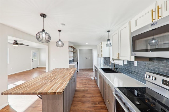 kitchen featuring a sink, decorative backsplash, butcher block countertops, appliances with stainless steel finishes, and white cabinetry