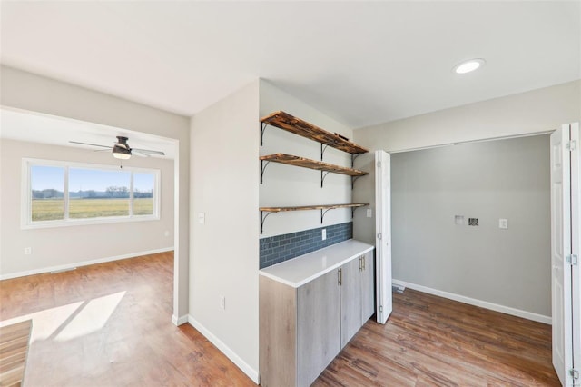 kitchen featuring wood finished floors, baseboards, open shelves, ceiling fan, and light countertops